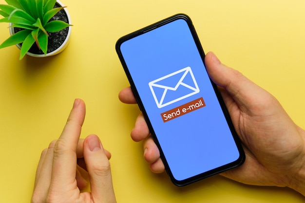 Persoon stuurt een e-mail met een smartphone in zijn handen.