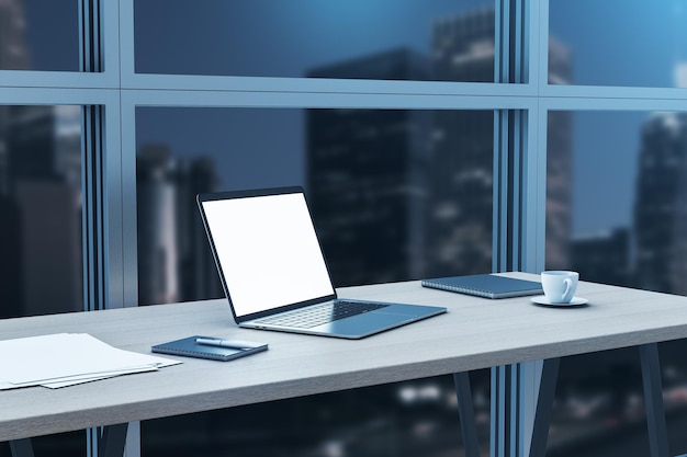 Perspectief uitzicht op houten werktafel met blanco witte laptop scherm met copyspace voor uw logo of tekst koffiemok en papieren op nacht uitzicht op de stad achtergrond 3D-rendering mockup