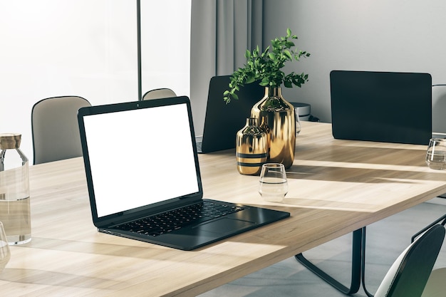 Perspectiefmening op leeg wit beeldscherm met plaats voor uw logo of tekst op houten vergadertafel met groene planten in gouden vazen op lichte muur achtergrond 3D-rendering mockup