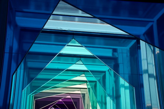 A perspective connection between buildings with blue green transparent glass partition