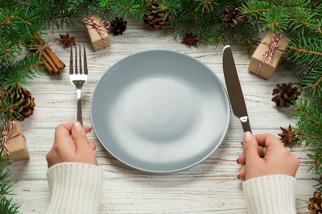 Perspective view girl holds fork and knife in hand and is ready to eat.