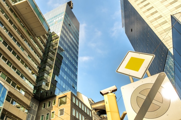 Perspective view of modern high-rise glass skyscraper building and main road traffic sign.