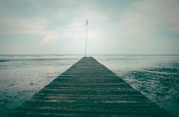 Photo perspective of wood bridge in deep sea.