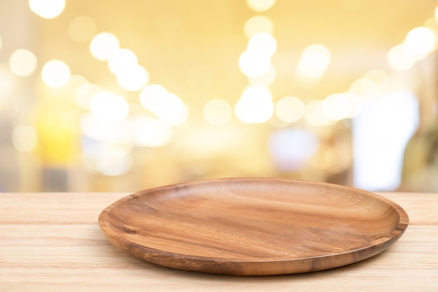 Perspective wooden table and wooden tray on top over blur bokeh light background.