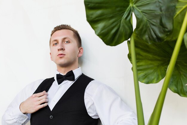 Perspective young man future generation of businessman stand\
near green plant on white background