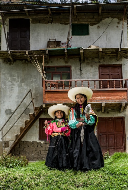 Foto peruaanse andes-meisjes die geweven stoffen maken en poseren in hun stad en huizen met gekleurde kleding