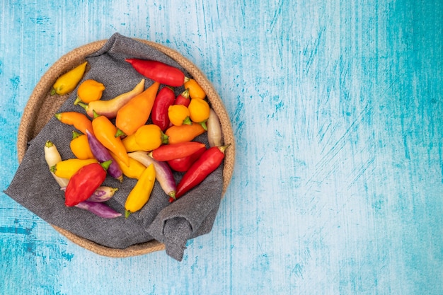 Peruaanse chilipepers van verschillende kleuren op blauwe tafel