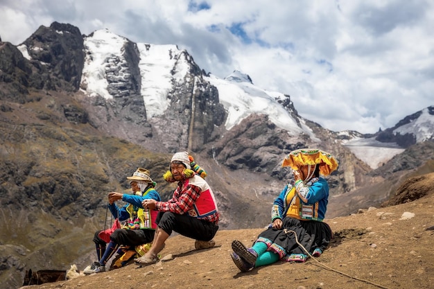 Peruanen in traditionele kleding zitten op een helling tegen de achtergrond van bergen in Peru