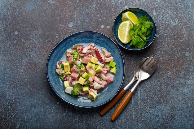 Peruvian ceviche with fresh fish, seafood, avocado on ceramic blue plate on rustic stone background from above, traditional dish of Peru cuisine