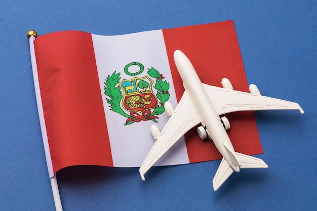 peruvian flag and a toy plane on a colored background, the concept on the theme of travel to peru