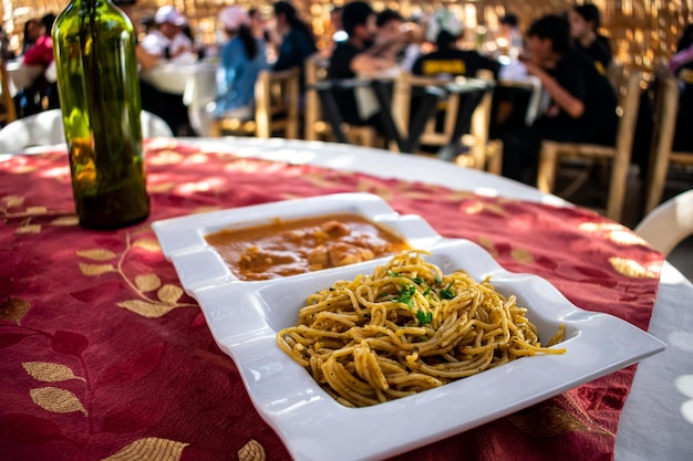 페루 음식 SOPA SECA CON CARAPULCRA, 이중 흰색 접시에 담긴 전통 식사.