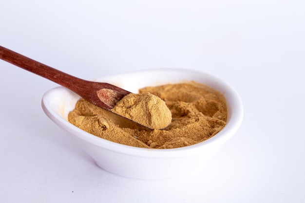 Peruvian maca powder with rustic wooden spoon on a white background selective focus