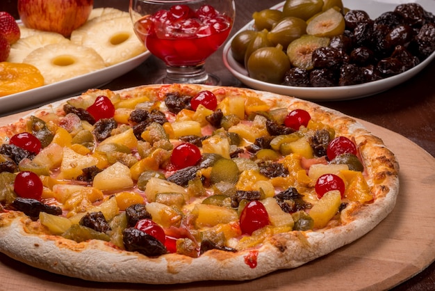 Perzik, kersen, pruimen, vijgen en ananas pizza op een houten bord. Braziliaanse zoete pizza.