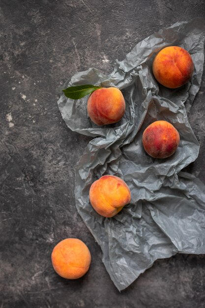 Perziken of nectarines in een grijze donkere stenen plaat met bladeren, bovenaanzicht