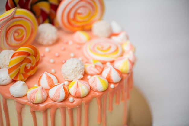 Perzikkleurige cake met meringue en snoep voor de verjaardag van een kind