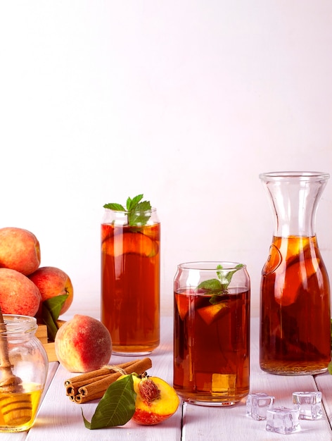 Perzikthee zomer koud drankje met ijsblokjes en munt op een witte achtergrond selectieve focus