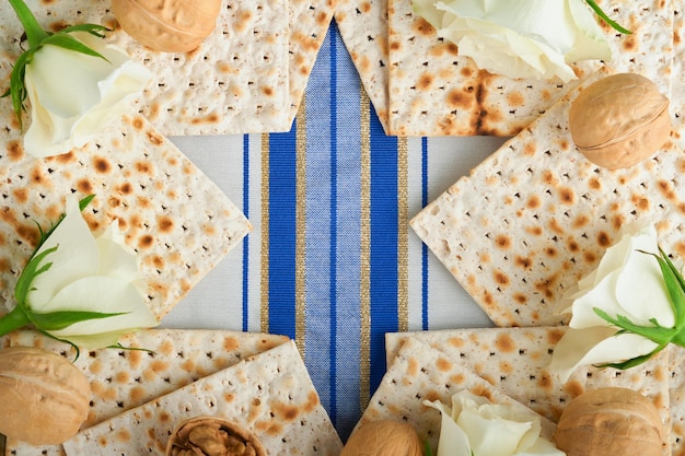 Pesach viering concept Blue Star of David gemaakt van matzah witte en gele rozen kippah en walnoot op bluebackground Traditioneel ritueel Joods Pascha eten Pesach Joodse feestdag Mock up