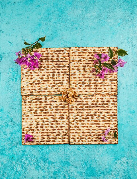 Pesach viering concept Joodse feestdag Pesach Vier vierkante gevouwen matzahs met bloemen Uitzicht van boven Platte lay-out