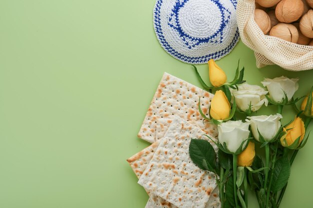 Pesach viering concept Matzah koosjere rode wijn walnoot en lente witte en gele rozenbloemen Traditioneel ritueel Joods brood op lichtgroene achtergrond Pesach voedsel Pesach Joodse feestdag