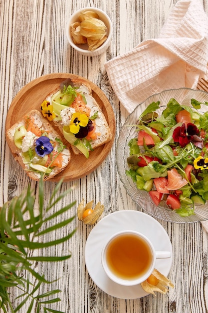 Пескетарианская еда тосты и салат с копченым лососем творог съедобные цветы овощи и зелень чашка чая эстетичный осенний обеденный перерыв