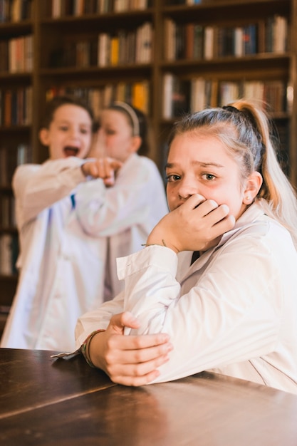 Foto pesters roddelen en spottende jonge huilende meisje