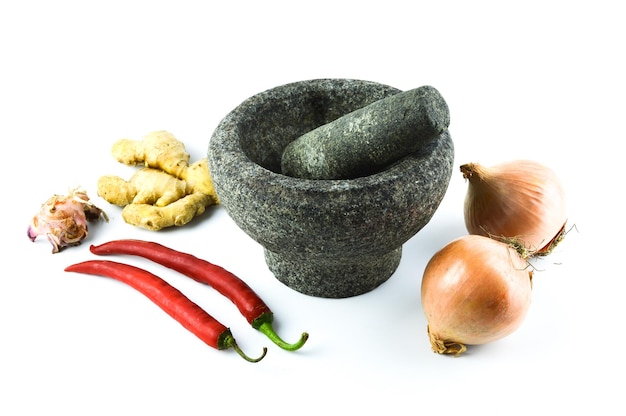 Pestle and mortar with the onions garlic red chilies and ginger over white background