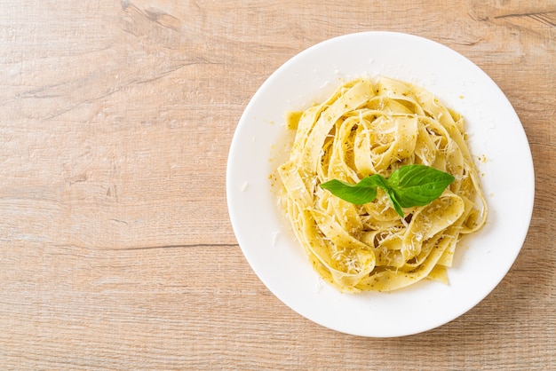 Photo pesto fettuccine pasta with parmesan cheese on top - italian food style