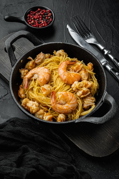 Pesto prawn pasta served, in cast iron frying pan, on black stone 