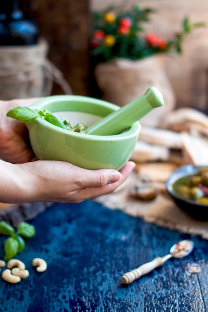 pesto sauce in a green cup and assorted salami on a wooden board a