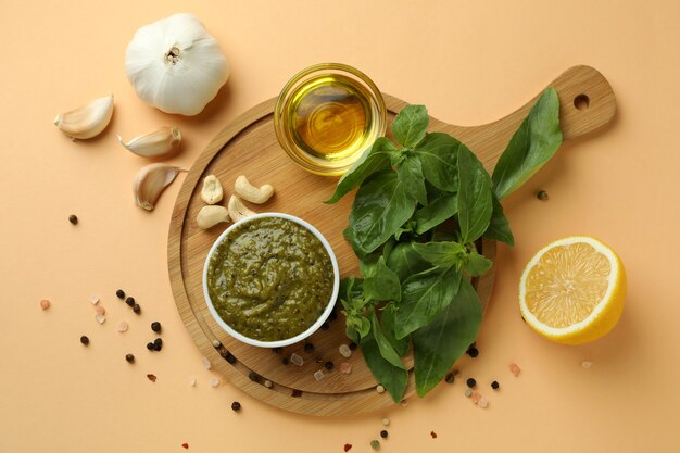 Pesto sauce and ingredients for cooking on beige background