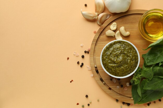 Pesto sauce and ingredients for cooking on beige background