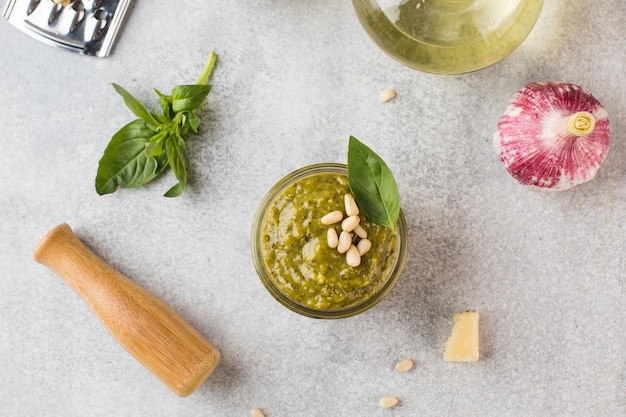 Pesto in vasetto con un pezzo di parmigiano basilico foglie pinoli e olio d'oliva in bottiglia cucina italiana