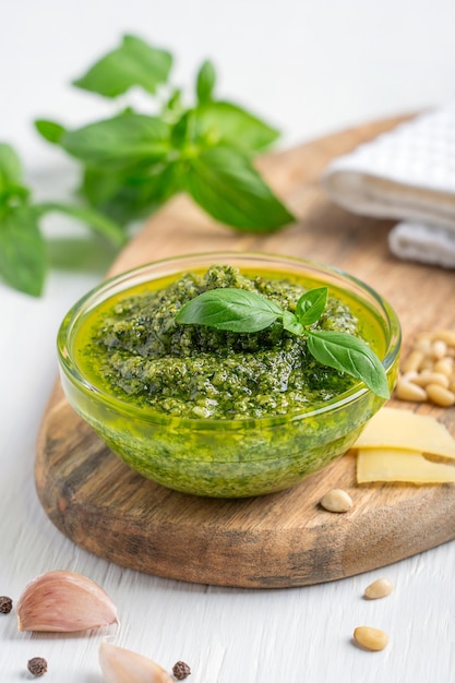 Salsa di pesto a base di pinoli aglio foglia di basilico e parmigiano servito in una ciotola su un tavolo di legno bianco