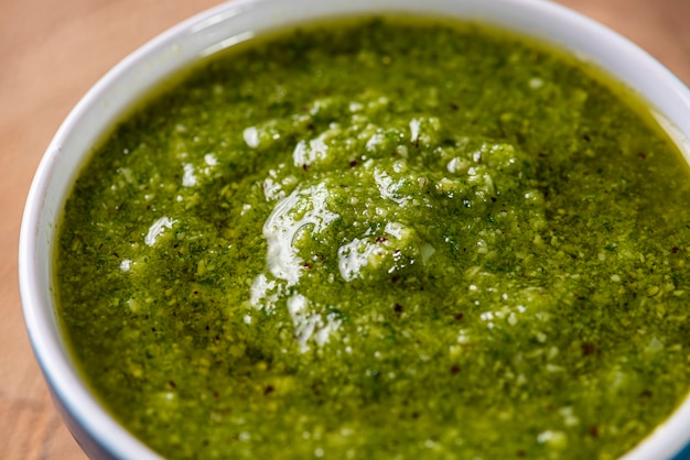 Photo pesto sauce. in a transparent glass with the ingredients in the surface. olive oil, garlic and basil.