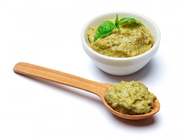 Foto salsa di pesto con basilico e cucchiaio di legno sulla tavola bianca