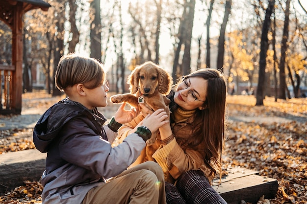 秋の幸せな家族の母親と 10 代の少年の息子が歩いてコッカーを楽しんでいるペットの世話のアドバイス