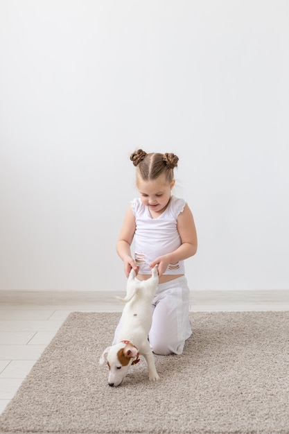 사진 애완 동물, 어린이 및 동물 개념 - 강아지를 발로 안고 있는 어린 소녀입니다.