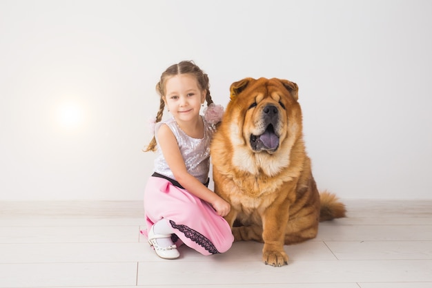 Animale domestico, bambini e concetto di famiglia - bambina e sua madre che abbracciano il cane chow-chow sopra bianco