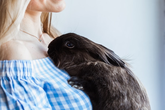 Pet and Easter concept - Attractive girl hugging brown rabbit at home, close-up.