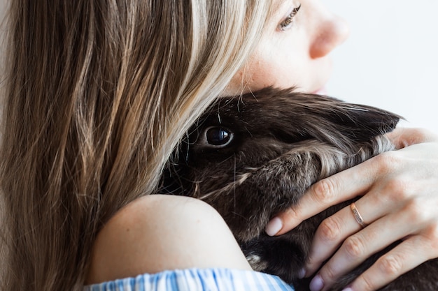 Pet and Easter concept - Attractive girl hugging brown rabbit at home, close-up.