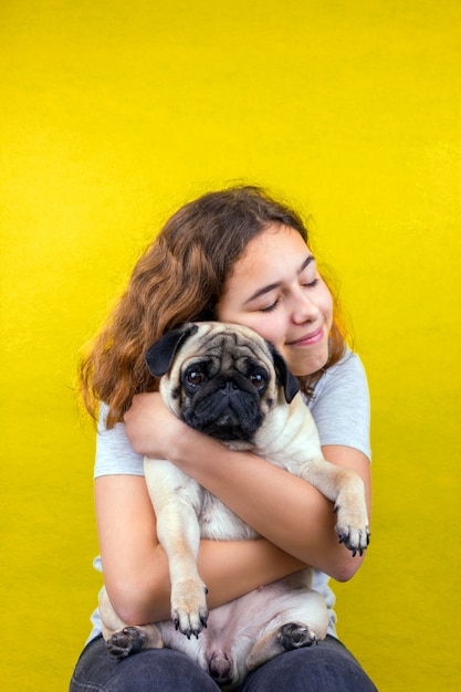 Photo pet love. curly teenager girl hugs her sad pug dog with love