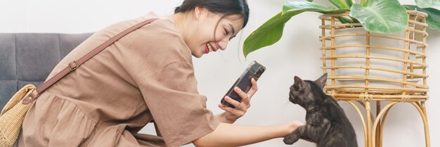 Pet lover concept Jonge Aziatische vrouw die smartphone gebruikt om een foto te maken van de kat in de woonkamer