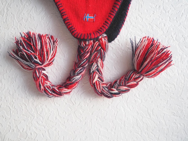 Pet met oorflappen in het noorse stijl gebreid mode-item met stropdassen en pomponkwastjes rood garen