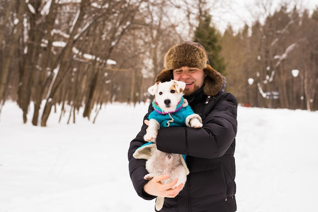 Концепция владельца домашних животных, собак и людей - молодой улыбающийся кавказский мужчина держит джек-рассел-терьера