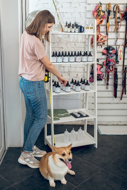 In a pet store. Cute young girl with her dog spending time in a pet store