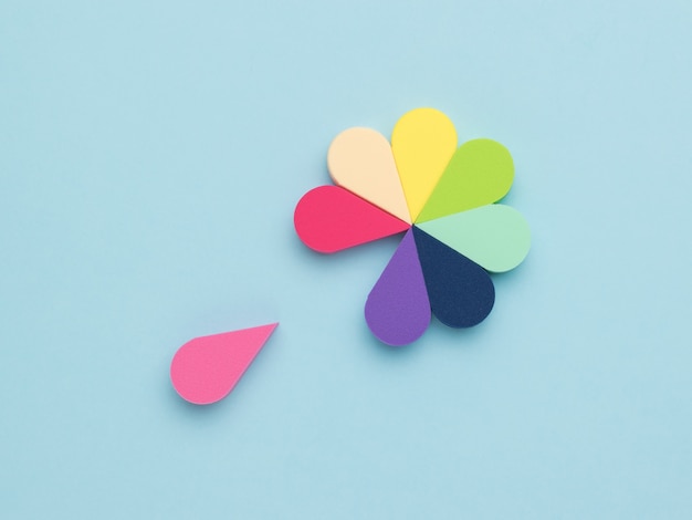 A petal separating from a multicolored flower of sponges on a blue surface