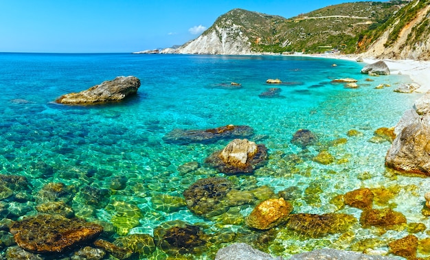 Взгляд лета пляжа Петани с большими камнями в воде Кефалония, Греция. Не всех людей узнают.