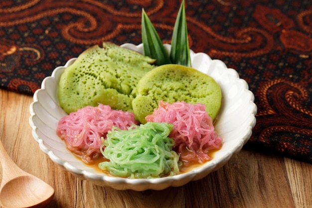 Pethulo srabi en putu mayang geserveerd met kokosmelk, palmsuikersiroop, traditioneel indonesisch dessert uit oost-java op houten tafel