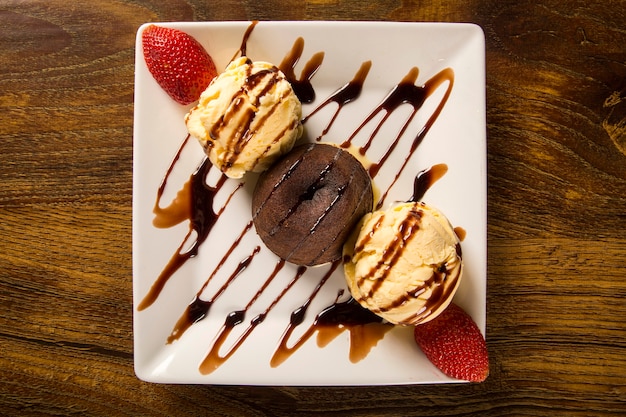 Petit gateau dessert with ice cream and strawberry on wooden table