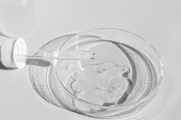petri dish with transparent gel with a pipette cosmetics bottle on a white background